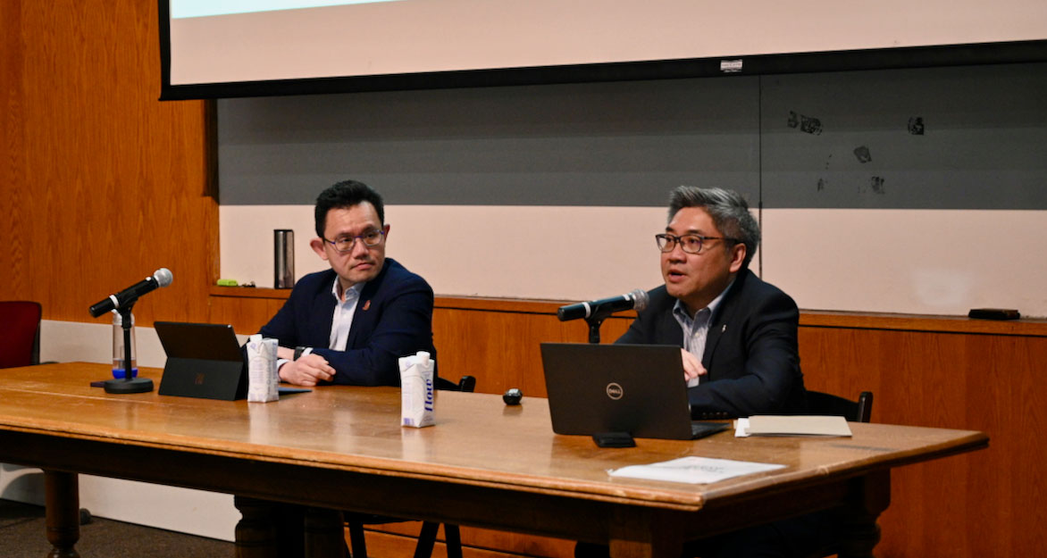 Ken-Chan and AnthonyYeung present the 2024 Victoria University budget at a table in a lecture hall.